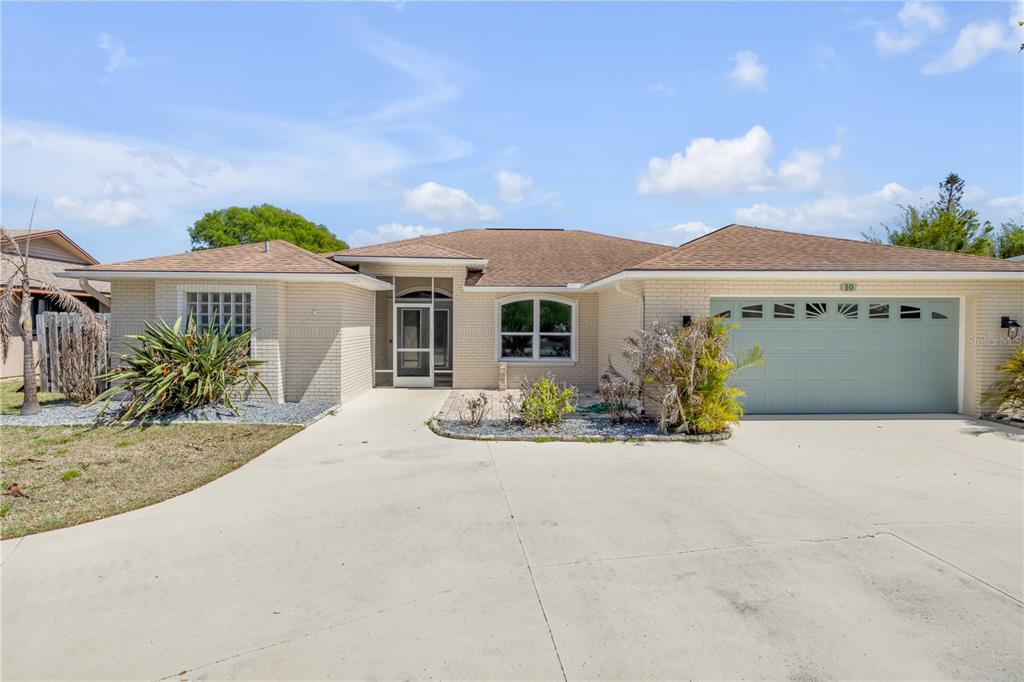 A single-story brick house with a two-car garage and a paved driveway — 10 CUNNINGHAM DRIVE, NEW SMYRNA BEACH, FL