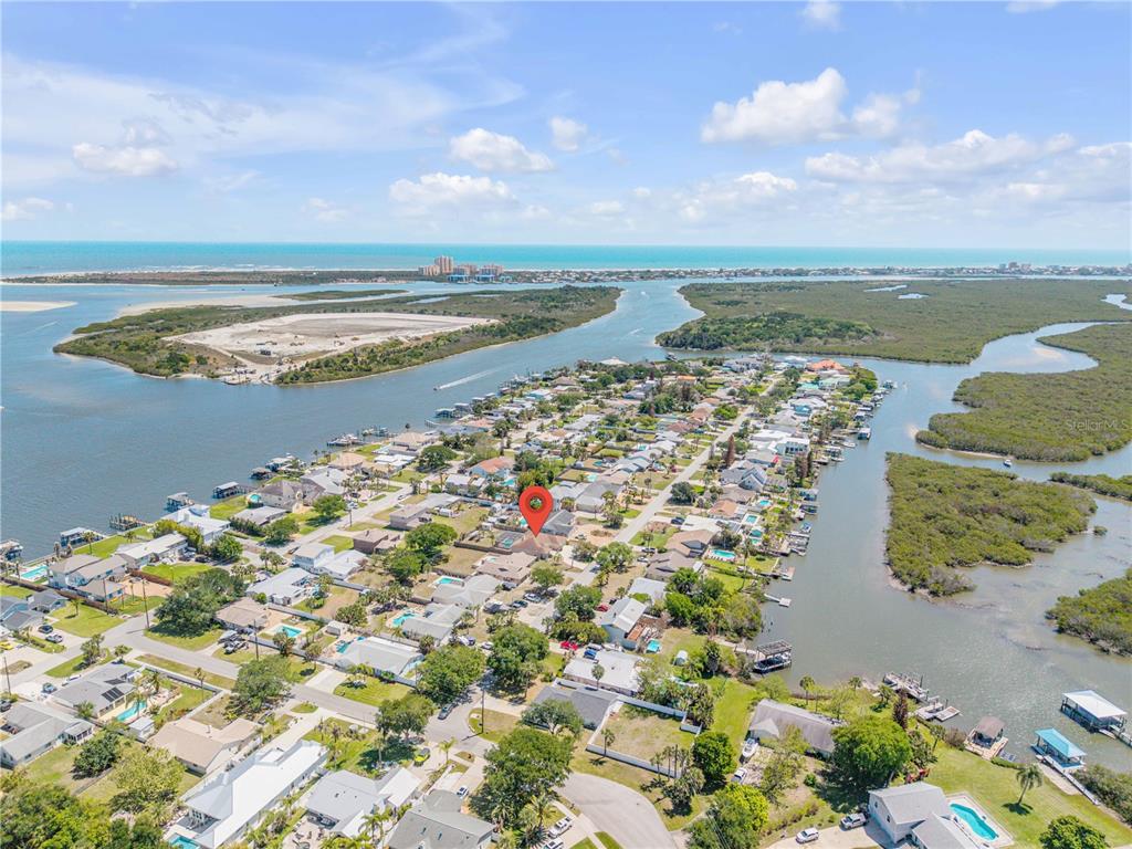 An aerial view shows a residential neighborhood surrounded by water and marshland — 10 CUNNINGHAM DRIVE, NEW SMYRNA BEACH, FL