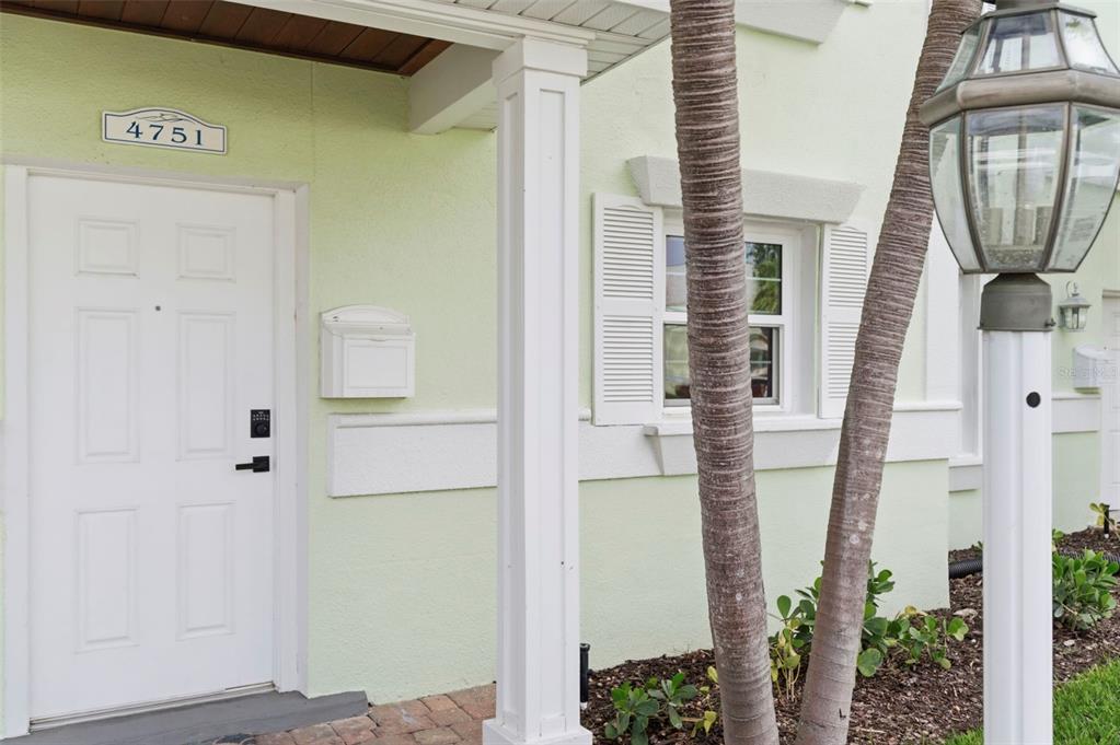 A light green exterior wall features a white front door, a mailbox, and a lamp post — 4751 COQUINA KEY DRIVE SE, ST PETERSBURG, FL