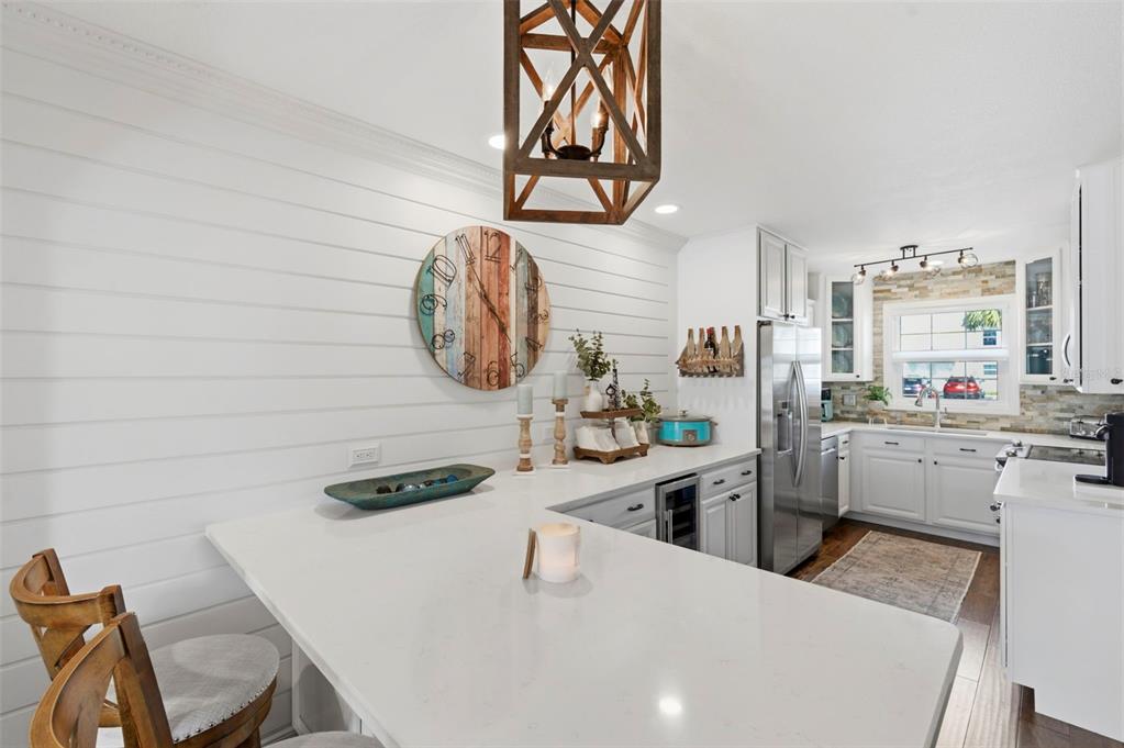 A bright kitchen features white shiplap walls, a quartz island, and a wooden pendant light — 4751 COQUINA KEY DRIVE SE, ST PETERSBURG, FL