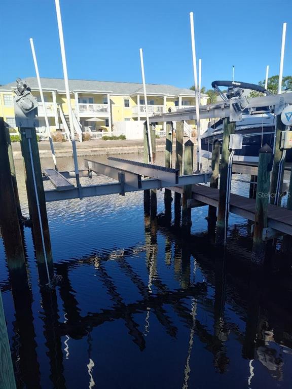 A boat lift sits in a canal in front of a yellow multi-story residential building — 127ss COQUINA KEY DR SE DRIVE, ST PETERSBURG, FL