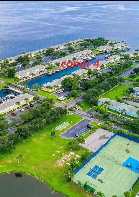 An aerial view shows a residential complex with a canal, tennis courts, and parking areas — 127ss COQUINA KEY DR SE DRIVE, ST PETERSBURG, FL