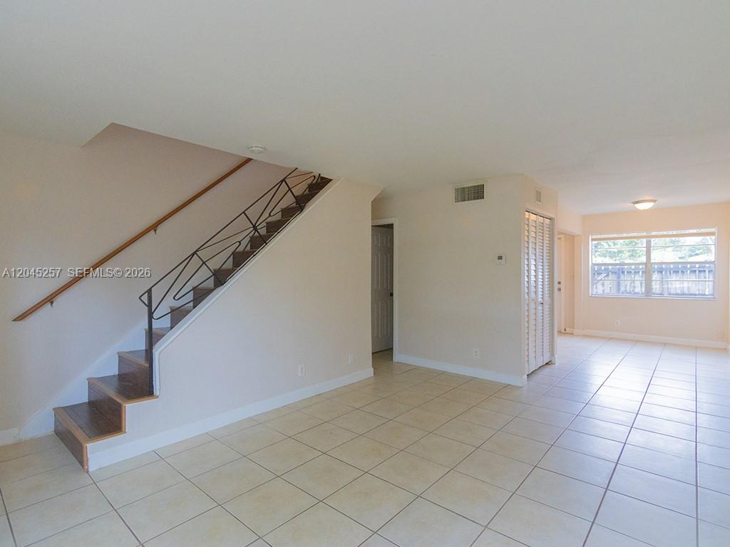 An interior view shows a tiled living area with a staircase and a window — 4648 NW 9th Dr # 4648, Plantation FL 33317, PLANTATION, FL