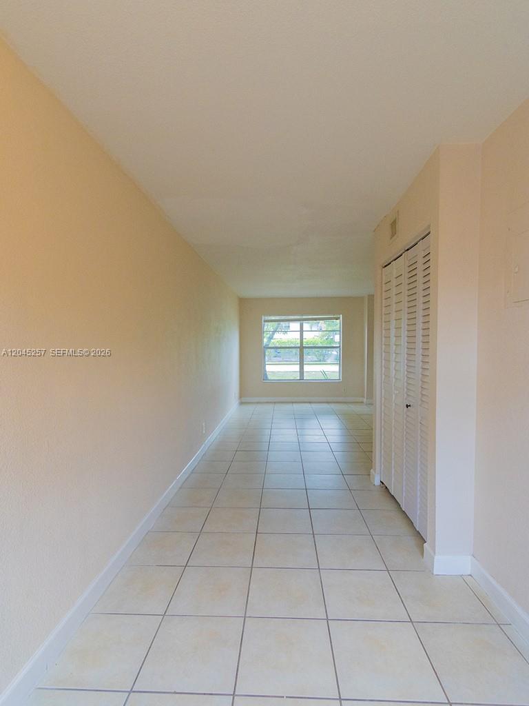 A long, narrow room features light-colored tile flooring, beige walls, and a white louvered closet — 4648 NW 9th Dr # 4648, Plantation FL 33317, PLANTATION, FL