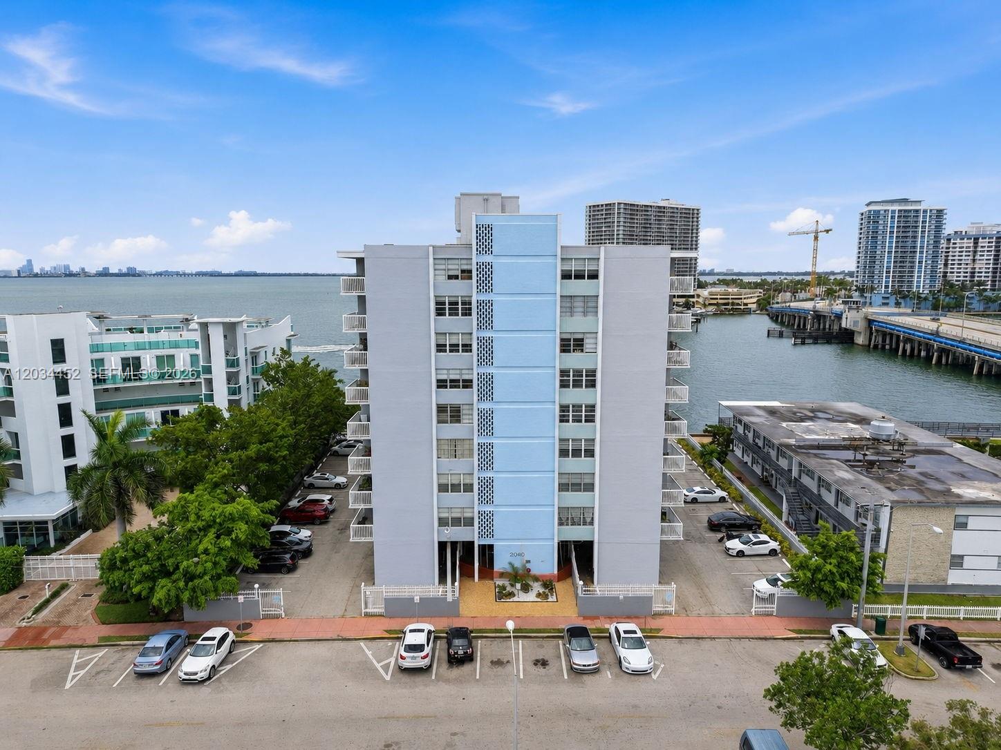 An aerial view shows a light blue and grey apartment building near a waterfront — 2016 Bay Dr # 504, Miami Beach FL 33141, MIAMI BEACH, FL