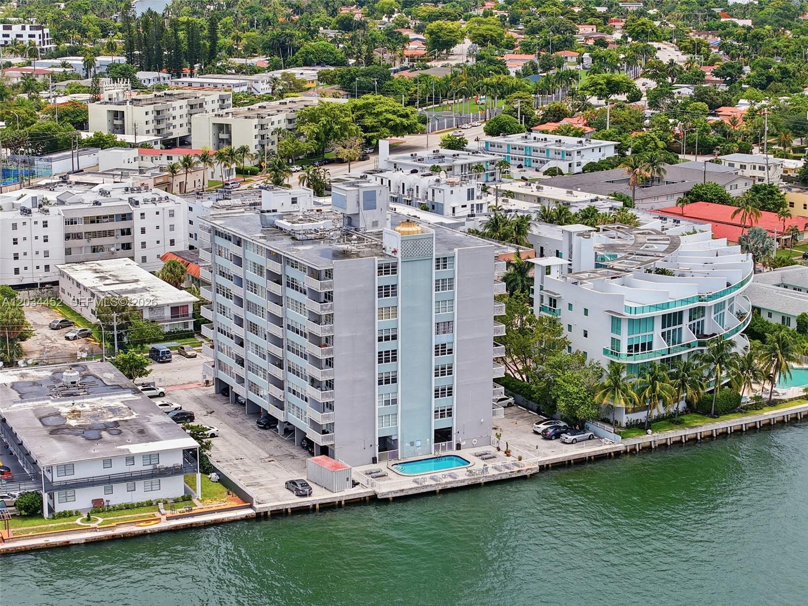 An aerial view shows a multi-story apartment building with a pool beside a waterway — 2016 Bay Dr # 504, Miami Beach FL 33141, MIAMI BEACH, FL