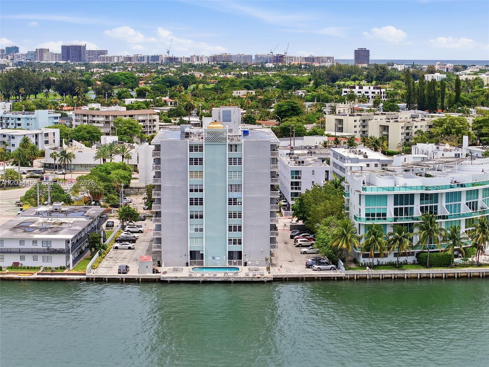 An aerial view shows a waterfront apartment building with a pool and parking lot — 2016 Bay Dr # 504, Miami Beach FL 33141, MIAMI BEACH, FL