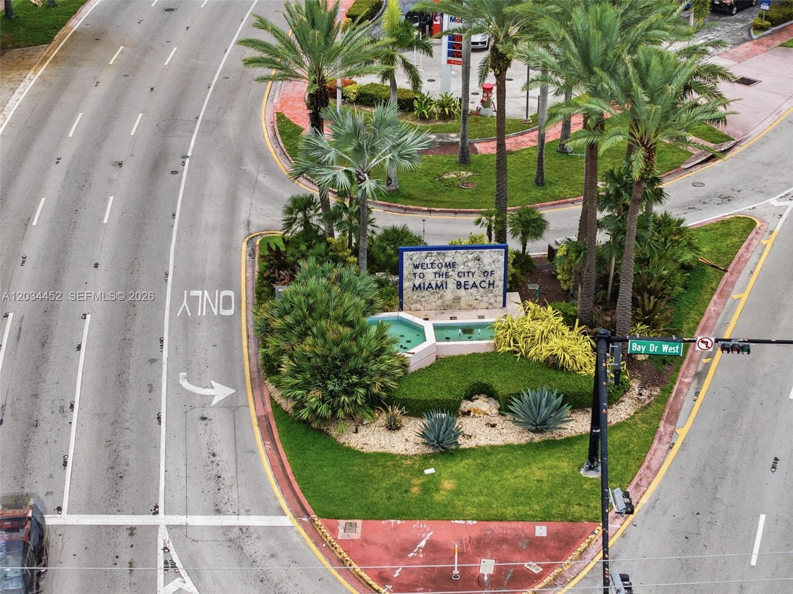An aerial view shows a landscaped island with a Miami Beach welcome sign and fountain — 2016 Bay Dr # 504, Miami Beach FL 33141, MIAMI BEACH, FL