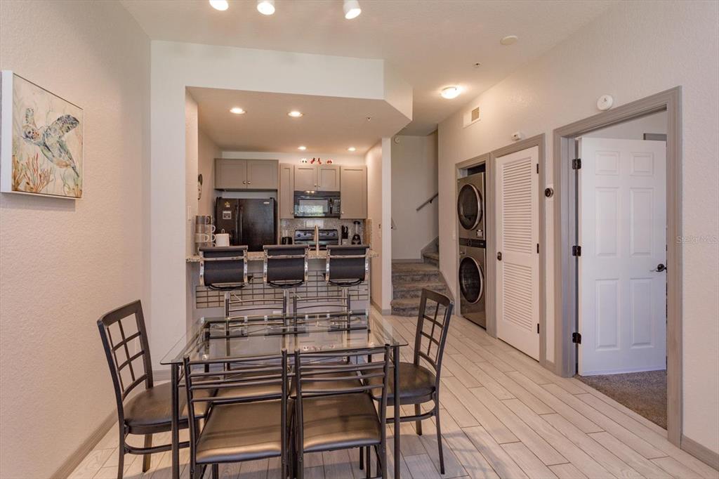A dining area with a glass table and bar seating opens into a small kitchen — 2211 SAN VITTORINO CIRCLE UNIT 103, KISSIMMEE, FL