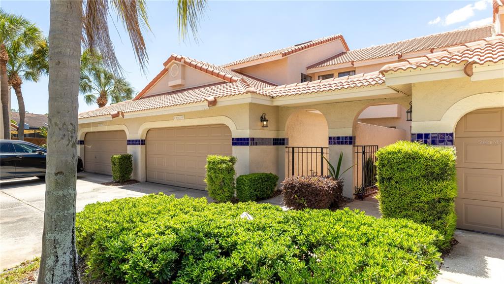 A two-story townhouse exterior features a double garage, a gated courtyard, and manicured landscaping — 10438 SAINT TROPEZ PLACE, TAMPA, FL