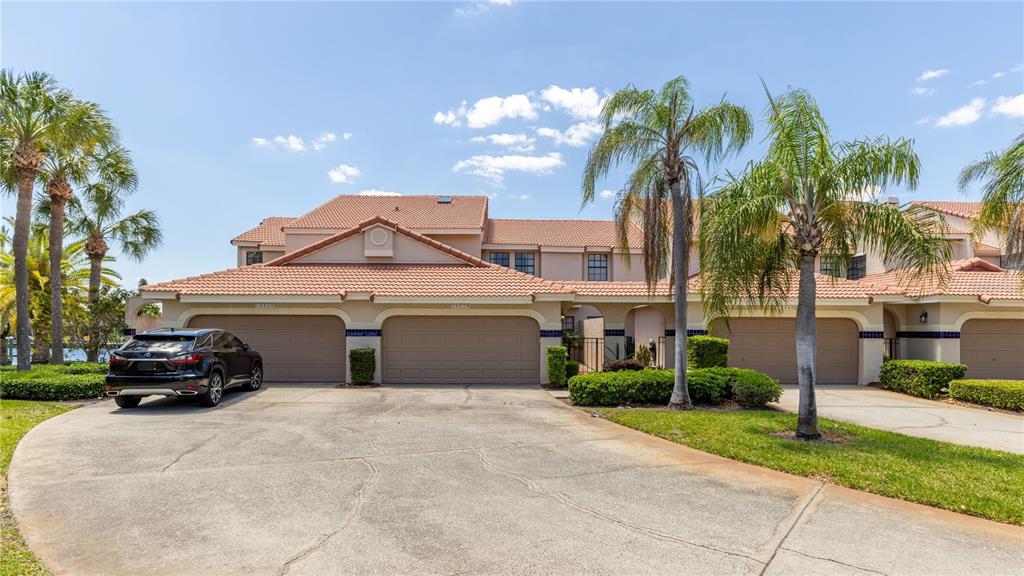 A multi-unit residential building with beige stucco walls, tiled roofs, and attached garages — 10438 SAINT TROPEZ PLACE, TAMPA, FL
