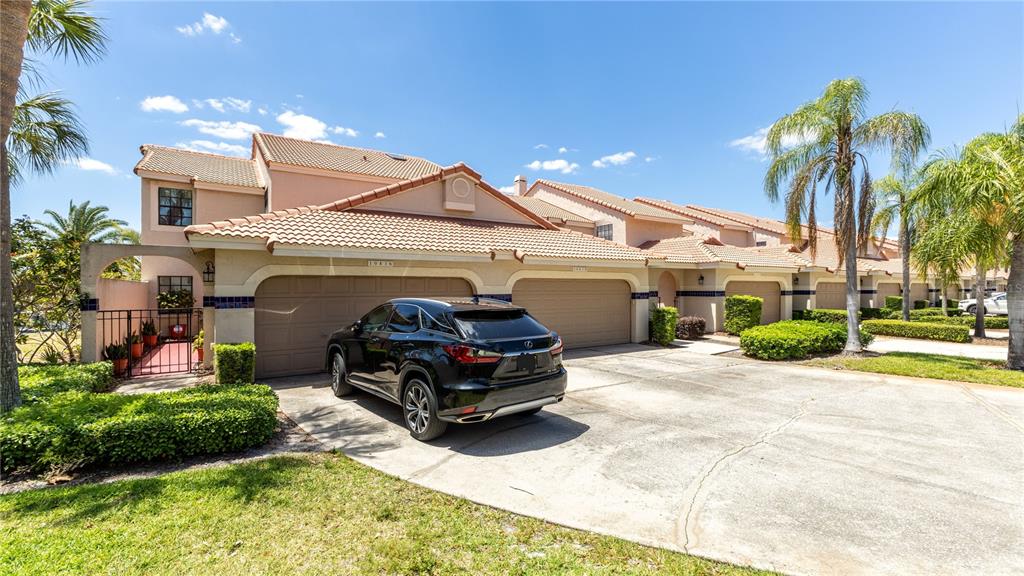 A black SUV is parked in front of a tan townhouse with a two-car garage — 10438 SAINT TROPEZ PLACE, TAMPA, FL