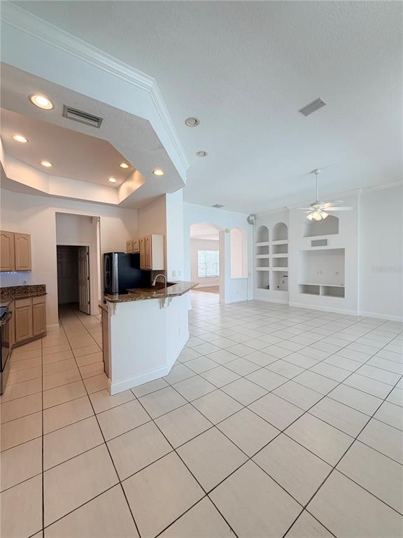 A kitchen with light cabinets and granite countertops opens into a tiled living area — 442 KNIGHT DRIVE, TARPON SPRINGS, FL
