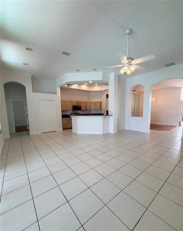 A spacious living area with tile flooring leads to an open kitchen with a breakfast bar — 442 KNIGHT DRIVE, TARPON SPRINGS, FL