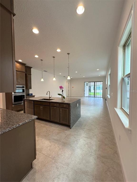 A kitchen with dark wood cabinets and granite countertops opens into a spacious living area — 13112 WEAVER AVENUE, ORLANDO, FL