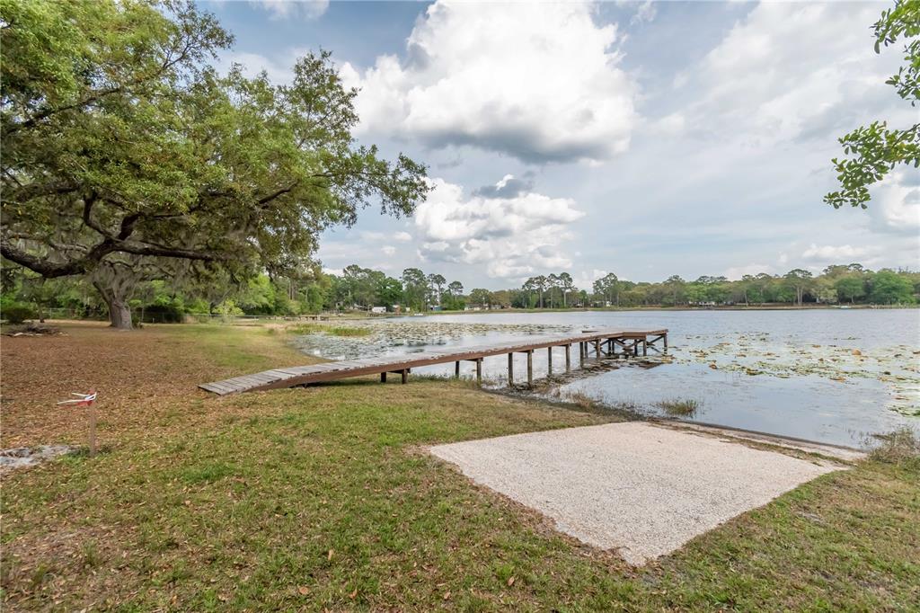 A wooden dock extends into a lake from a grassy yard with a gravel boat ramp — 22649, 22645 and TBD NE 105TH AVENUE ROAD, FORT MC COY, FL