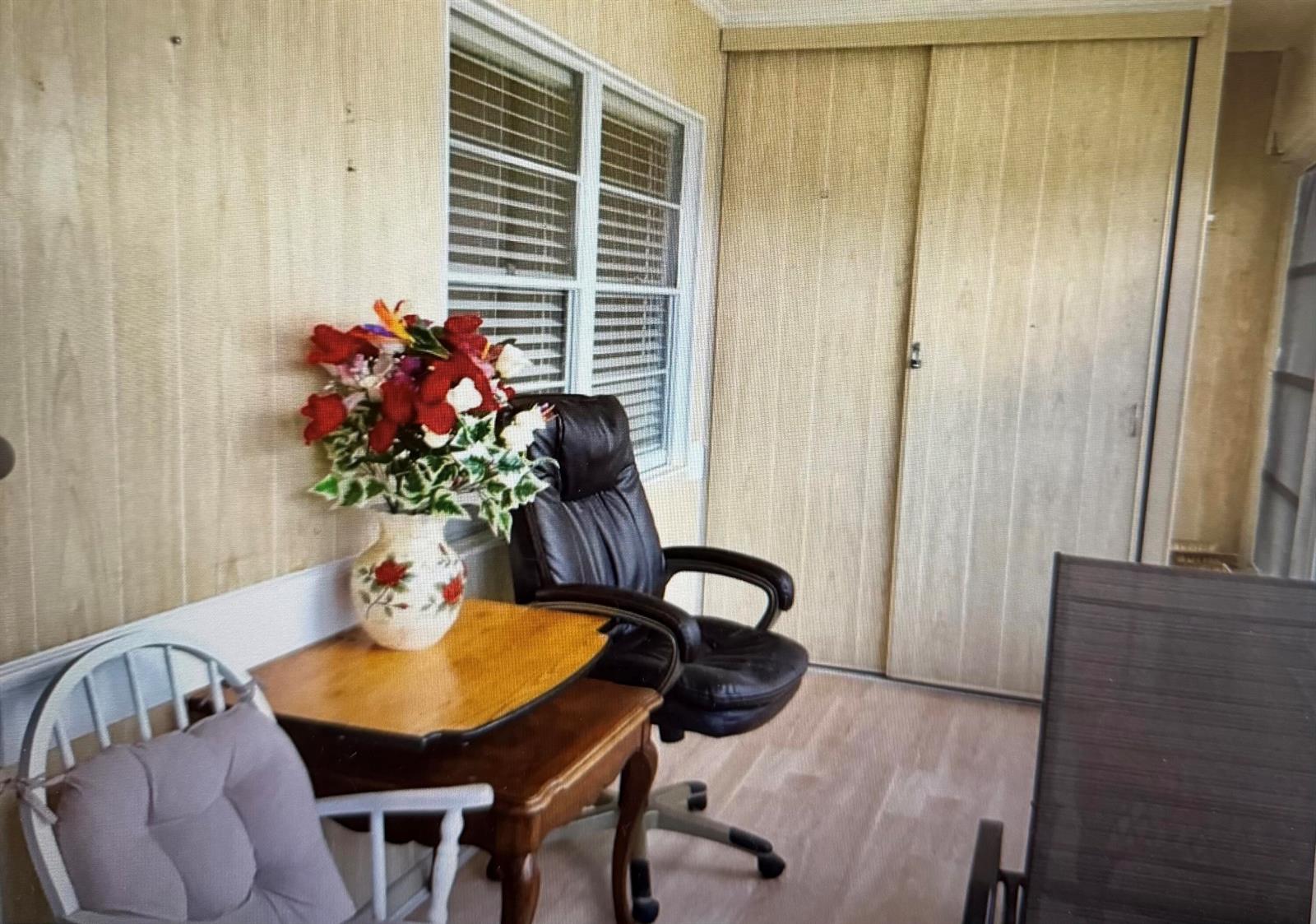 A sunroom features wood-paneled walls, light flooring, a window with blinds, and a small table — 2038 Exeter C, Boca Raton FL 33434, BOCA RATON, FL