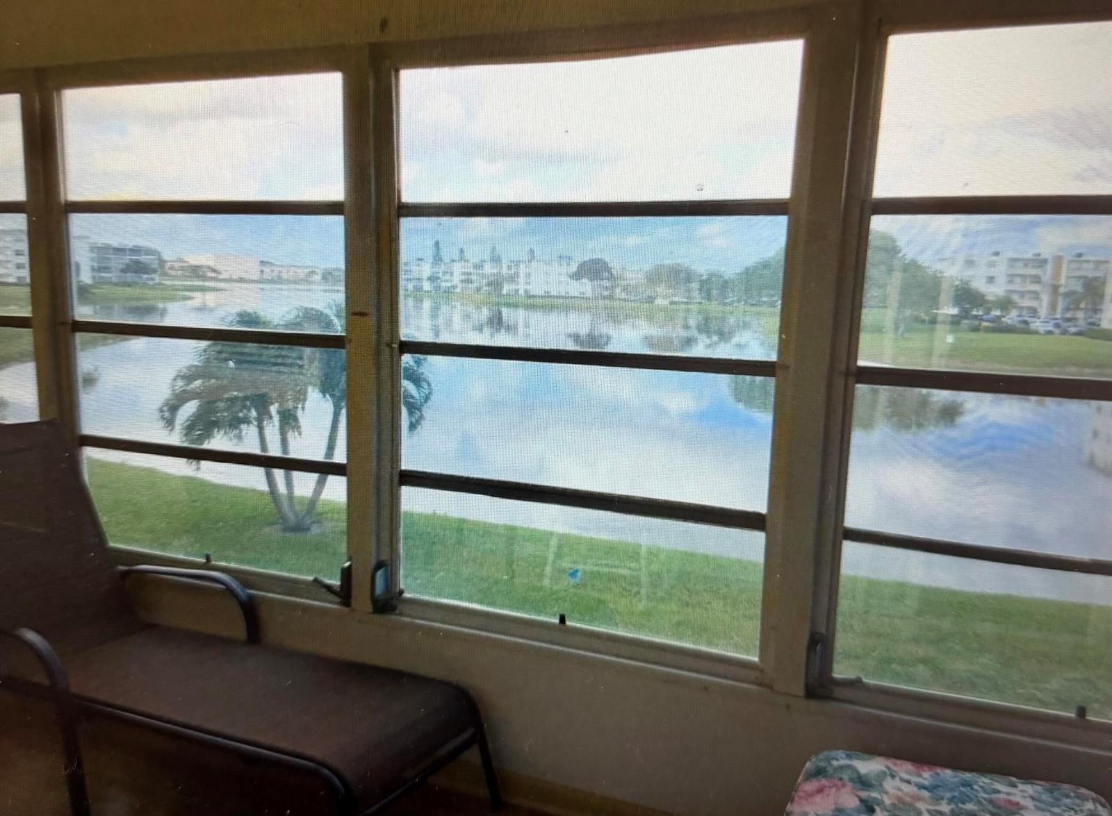 A view of a lake and residential buildings through a screened-in porch window — 2038 Exeter C, Boca Raton FL 33434, BOCA RATON, FL