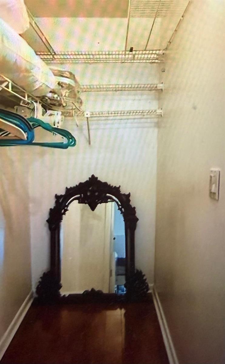 A walk-in closet features wire shelving, hardwood flooring, and a large ornate floor mirror — 2038 Exeter C, Boca Raton FL 33434, BOCA RATON, FL