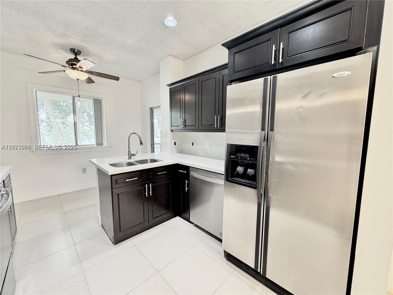 A kitchen features dark wood cabinets, stainless steel appliances, white countertops, and light tile flooring — 16320 Malibu Dr # 10, Weston FL 33326, WESTON, FL