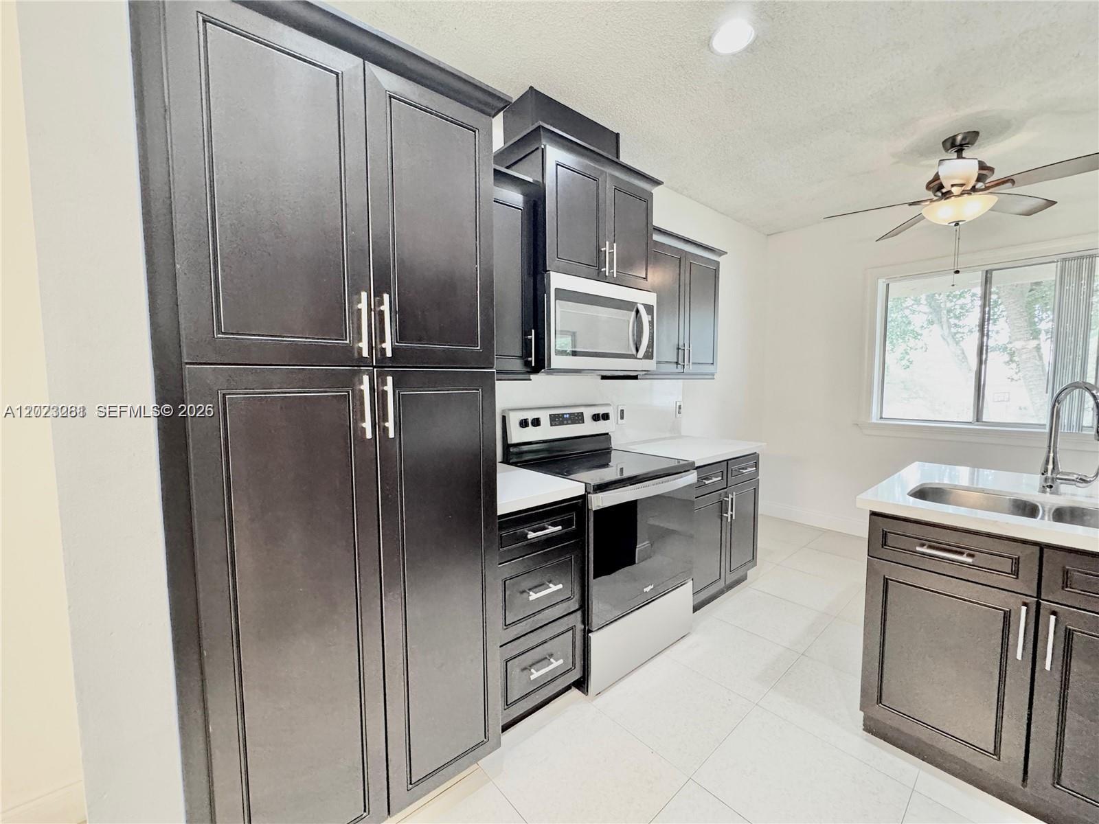 A kitchen features dark wood cabinets, stainless steel appliances, and light-colored tile flooring — 16320 Malibu Dr # 10, Weston FL 33326, WESTON, FL
