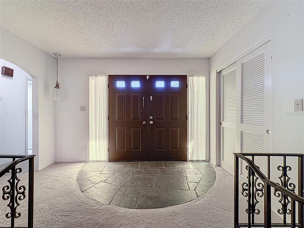 An entryway features a stone floor inlay, double doors with sidelights, and decorative metal railings — 9811 WOODSTOCK LANE, PORT RICHEY, FL