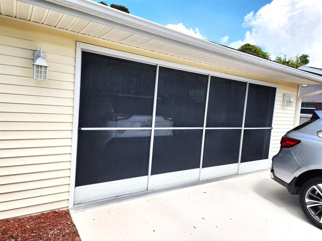 A garage door opening is covered by a sliding screen system on a residential home — 11660 SW 89TH TERRACE, OCALA, FL