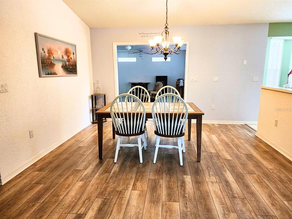 A dining room features a wooden table with four white chairs and wood-look flooring — 11660 SW 89TH TERRACE, OCALA, FL