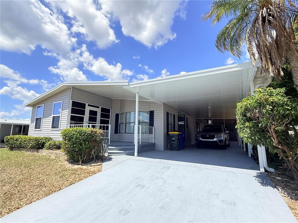 A single-story house with a gray exterior, a screened-in porch, and a covered carport — 116 S WINTER CIRCLE, AVON PARK, FL