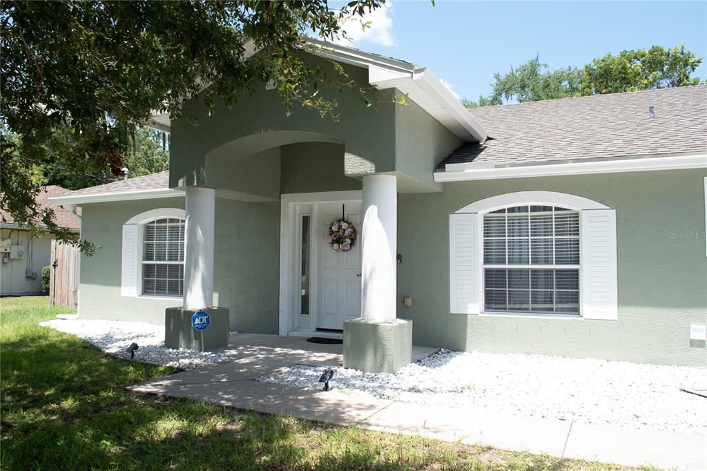 A single-story house with green stucco walls, white columns, and a covered front entryway — 15 POINSETTIA LANE, PALM COAST, FL