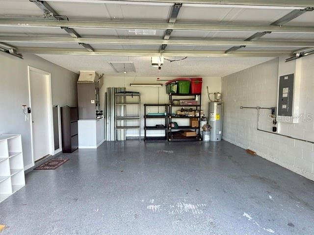 A spacious garage features a concrete floor, metal shelving units, and a water heater — 15 POINSETTIA LANE, PALM COAST, FL