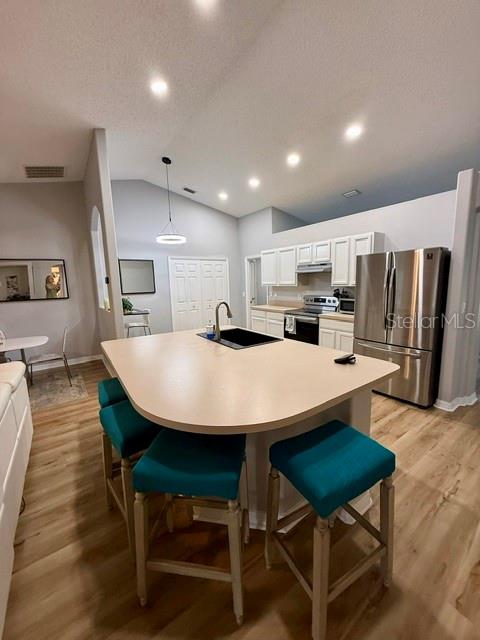 A kitchen features a central island with a sink, teal barstools, and stainless steel appliances — 15 POINSETTIA LANE, PALM COAST, FL