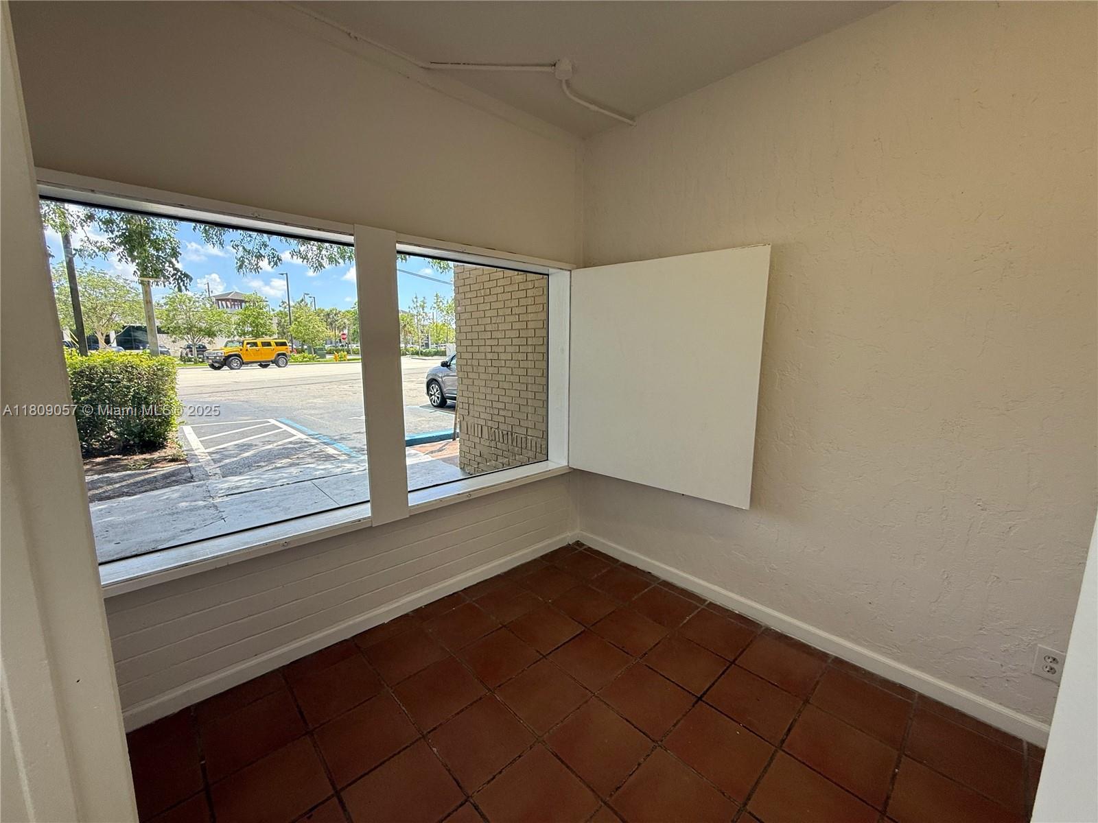 A small room with brown tile flooring, white walls, and two windows overlooking a parking lot — 8320 SW 124th St, Pinecrest FL 33156, PINECREST, FL