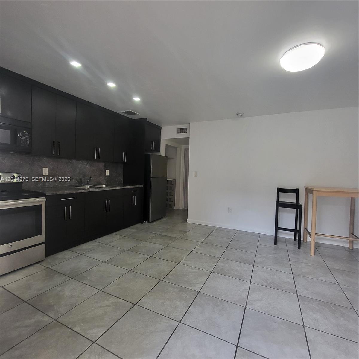 A kitchen features dark cabinets, stainless steel appliances, and gray tile flooring — 315 NW 59th St # 2, Miami FL 33127, MIAMI, FL