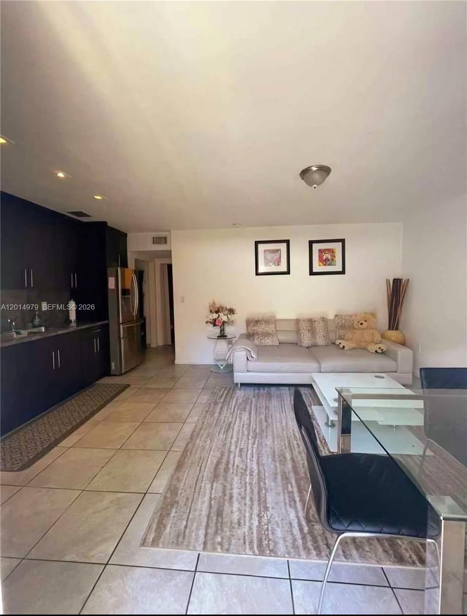 A kitchen with dark cabinets opens into a living area with a sofa and rug — 315 NW 59th St # 2, Miami FL 33127, MIAMI, FL