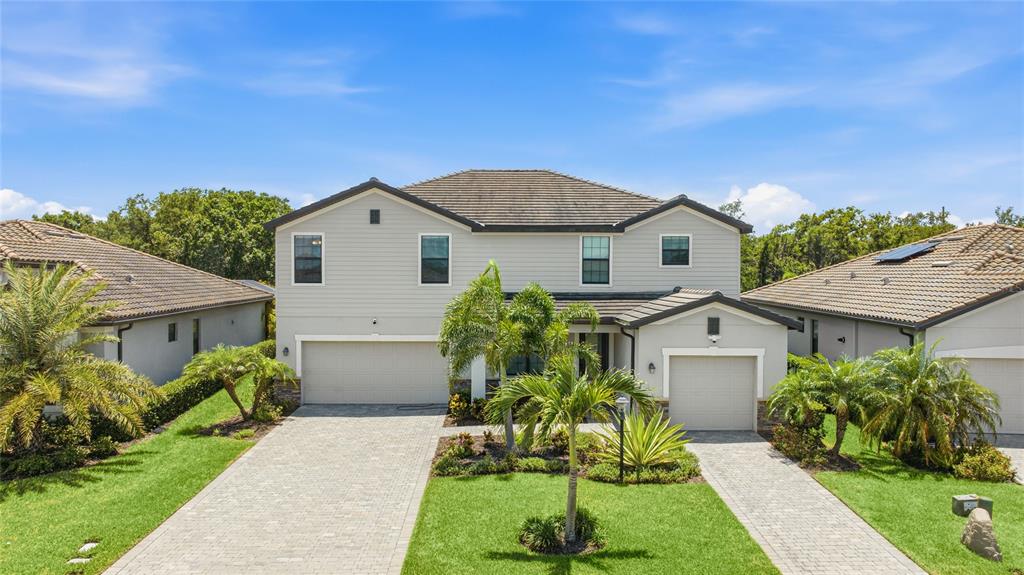 A two-story house with a light gray exterior, two garages, and a paved driveway — 17821 POLO TRAIL, BRADENTON, FL