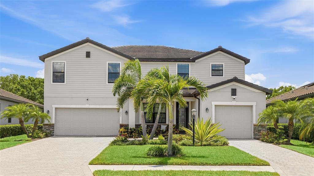 A two-story suburban house with a gray exterior, two garages, and a landscaped front yard — 17821 POLO TRAIL, BRADENTON, FL