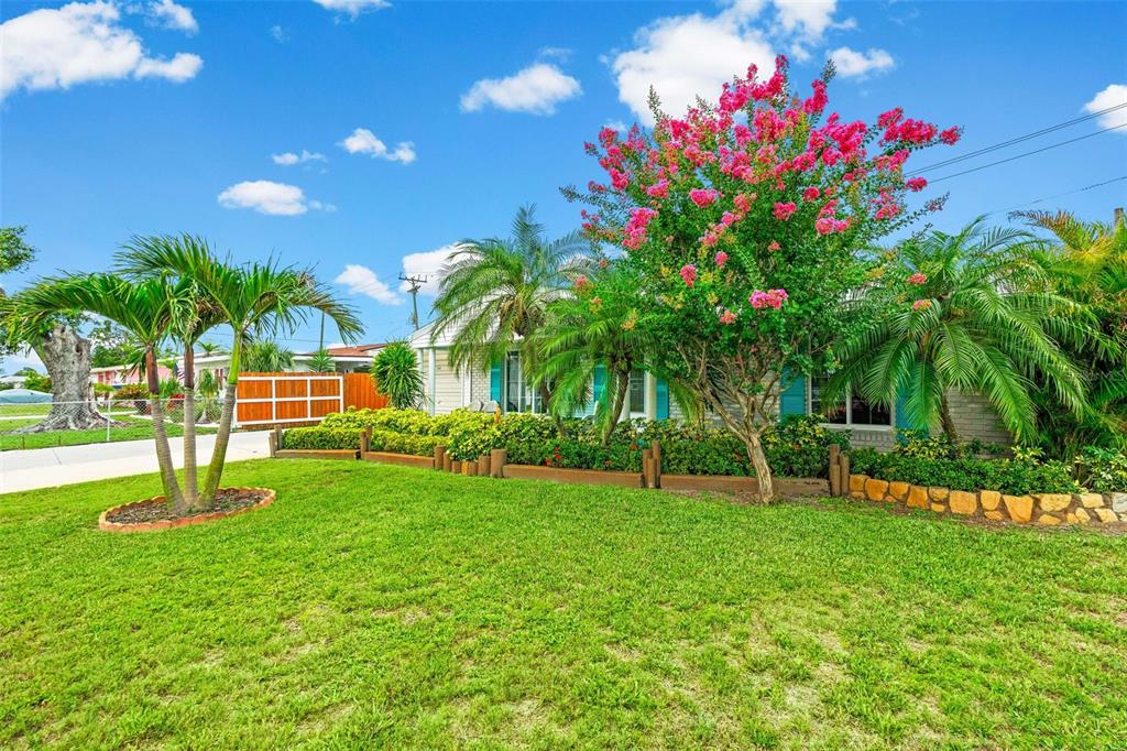 A single-story house with a green lawn, palm trees, and a blooming crape myrtle tree — 2545 EDNOR STREET, PORT CHARLOTTE, FL
