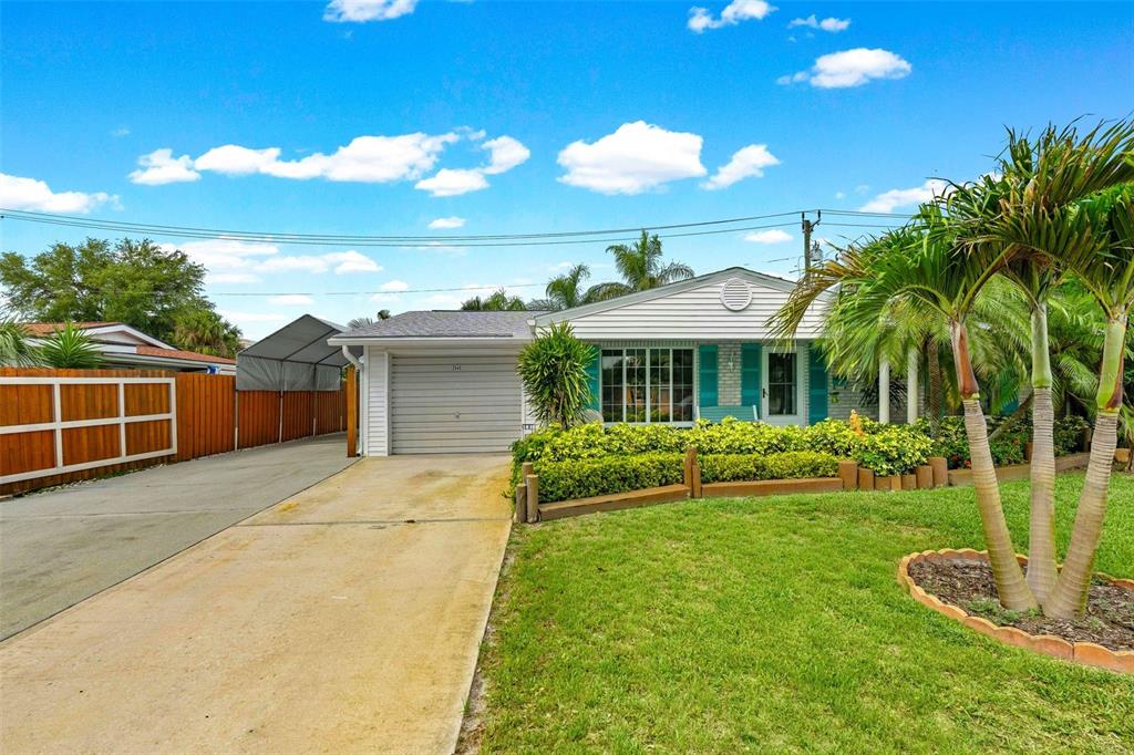 A single-story house with a concrete driveway, a garage, and a front lawn with palm trees — 2545 EDNOR STREET, PORT CHARLOTTE, FL