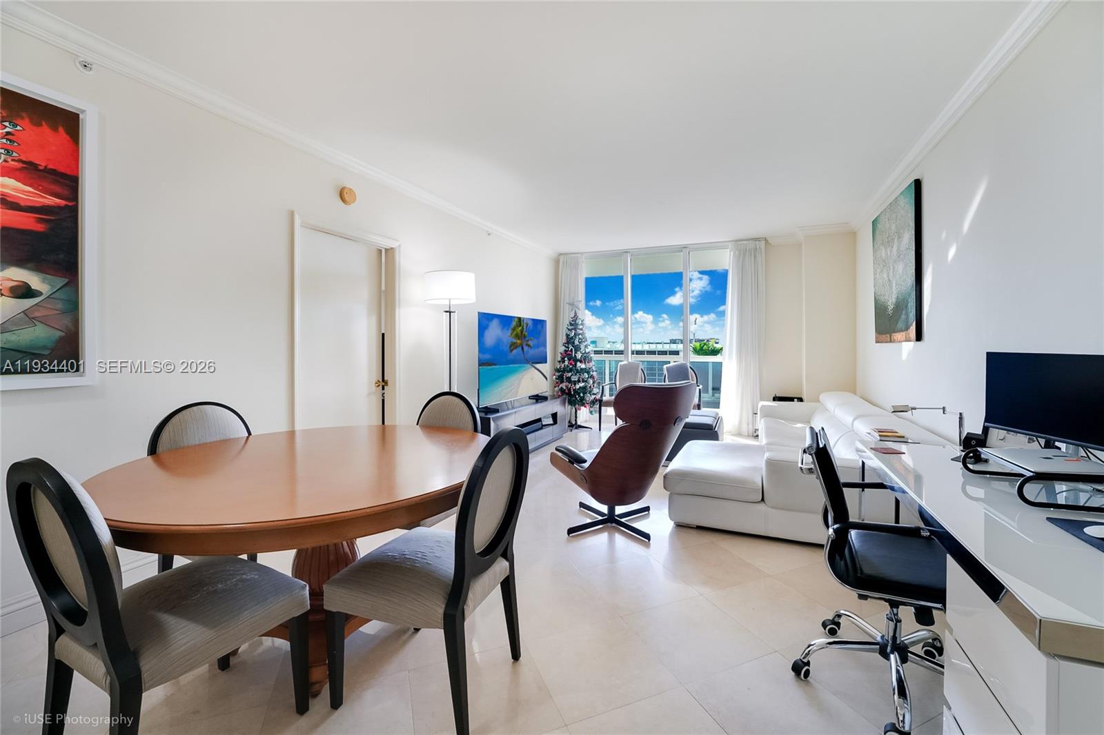 A bright living and dining area features tile floors, a white sofa, and balcony views — 9559 Collins Ave # F, Surfside FL 33154, SURFSIDE, FL