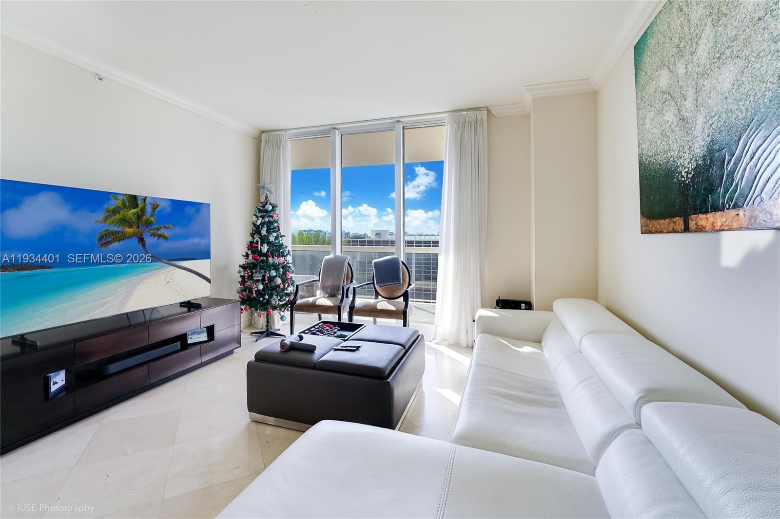 A living room features a white sectional sofa, a large television, and floor-to-ceiling windows — 9559 Collins Ave # F, Surfside FL 33154, SURFSIDE, FL