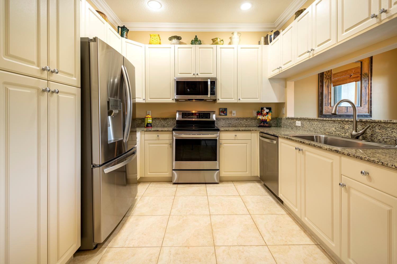 A kitchen features cream cabinets, stainless steel appliances, granite countertops, and light-colored tile flooring — 3501 Lakeside Drive, Davie FL 33328, DAVIE, FL
