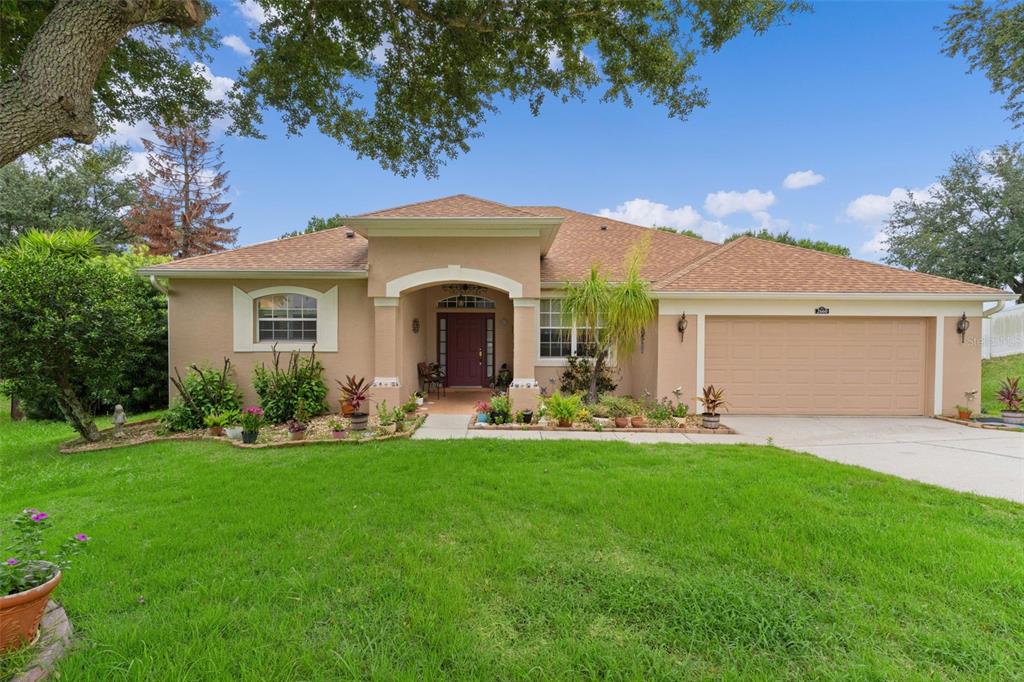 A single-story tan stucco house with a two-car garage and a covered front entryway — 2660 LEDGEMONT COURT, CLERMONT, FL