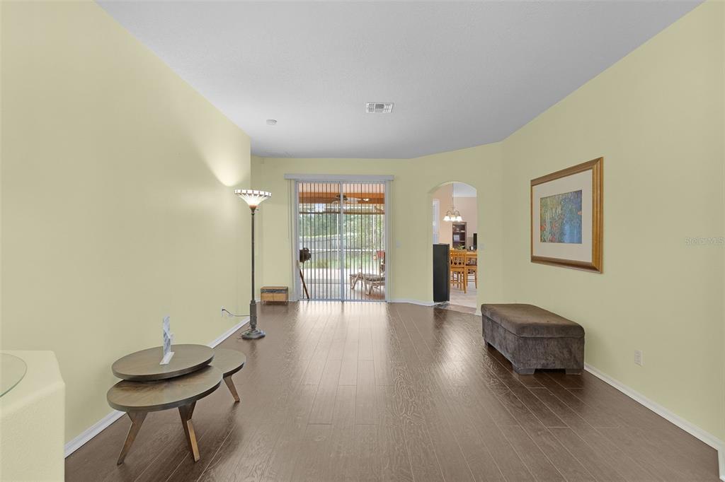 A living room with light yellow walls, dark wood flooring, and a sliding glass door — 2660 LEDGEMONT COURT, CLERMONT, FL