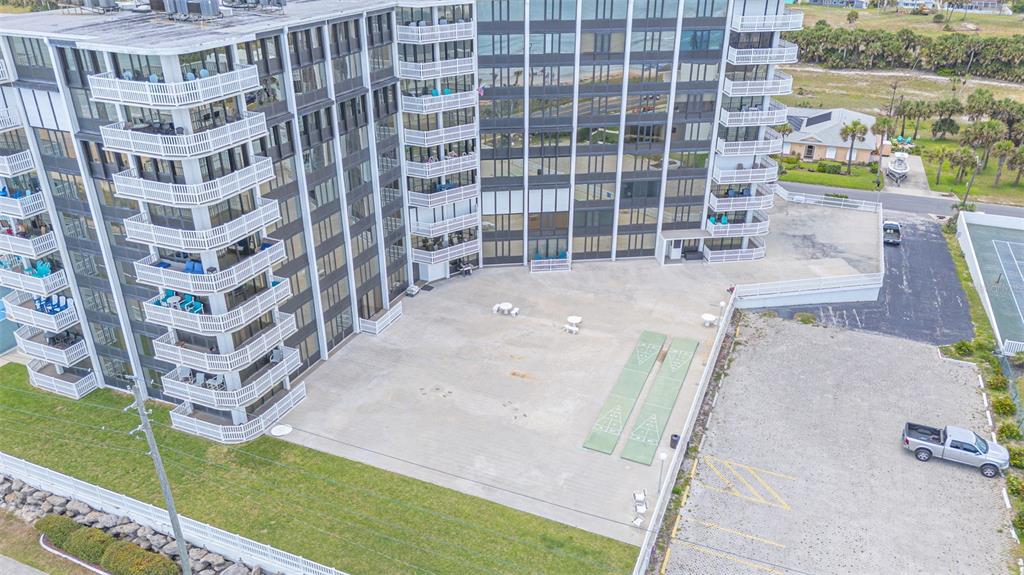 An aerial view shows a multi-story apartment building with balconies, a concrete patio, and shuffleboard courts — 3580 S OCEAN SHORE BOULEVARD UNIT 404, FLAGLER BEACH, FL