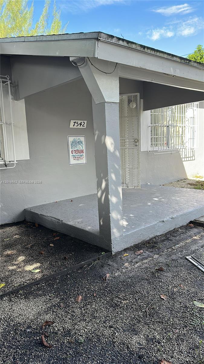 The exterior of a house features a covered concrete porch and a metal security door — MIAMI, FL