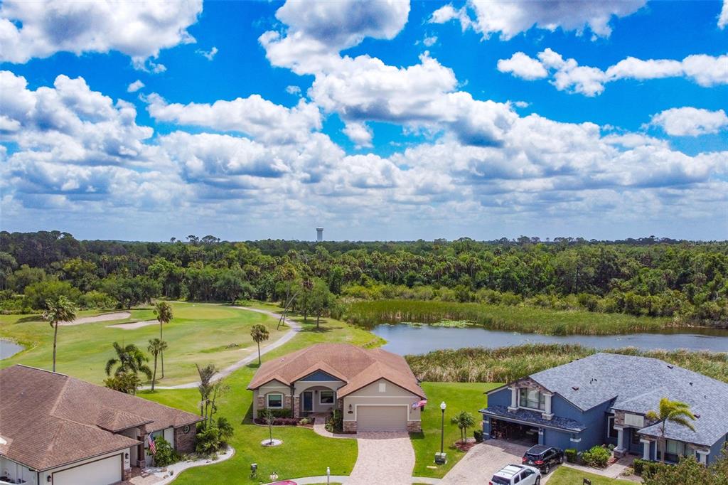 An aerial view shows three suburban houses situated next to a golf course and pond — 8602 AMEN CORNER PLACE, PALMETTO, FL