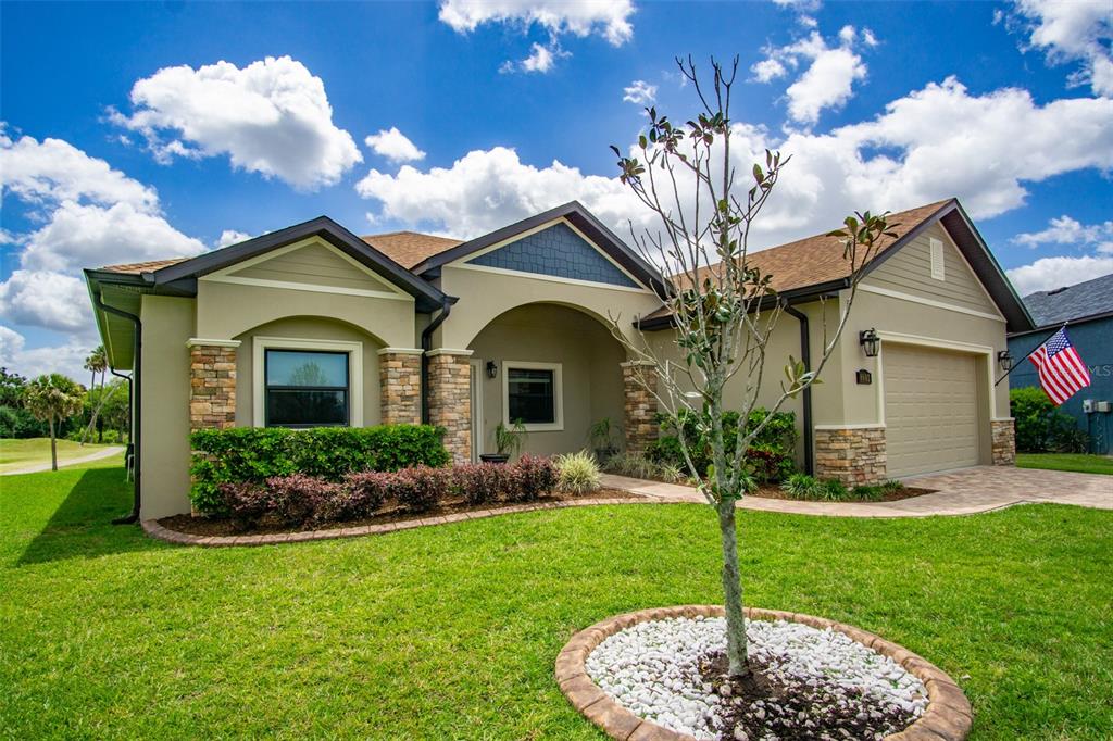 A single-story house with a tan stucco exterior, stone accents, and a front-facing garage — 8602 AMEN CORNER PLACE, PALMETTO, FL