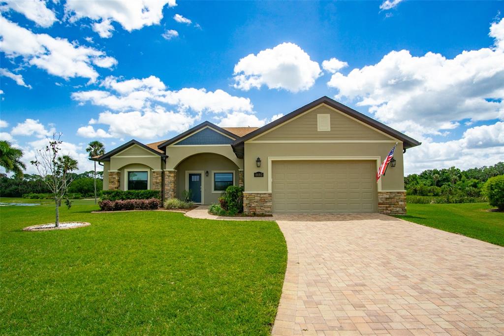A single-story house with a beige exterior, stone accents, and a paved driveway — 8602 AMEN CORNER PLACE, PALMETTO, FL