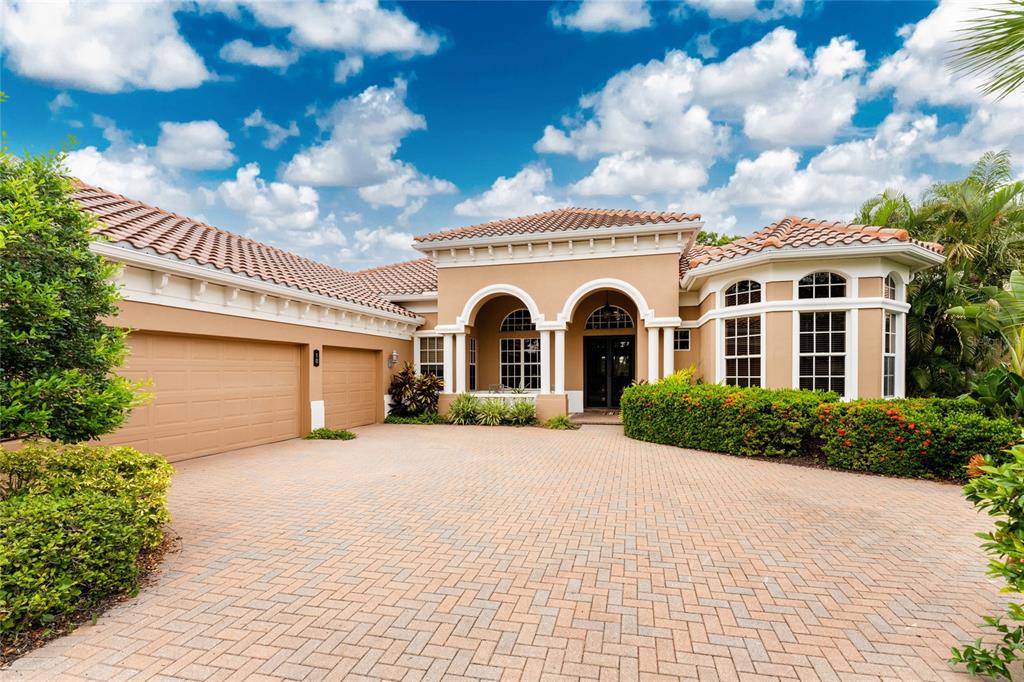 A tan single-story house with a tiled roof, arched entryway, and a brick paver driveway — 10 BOCA ROYALE BLVD BOULEVARD, ENGLEWOOD, FL